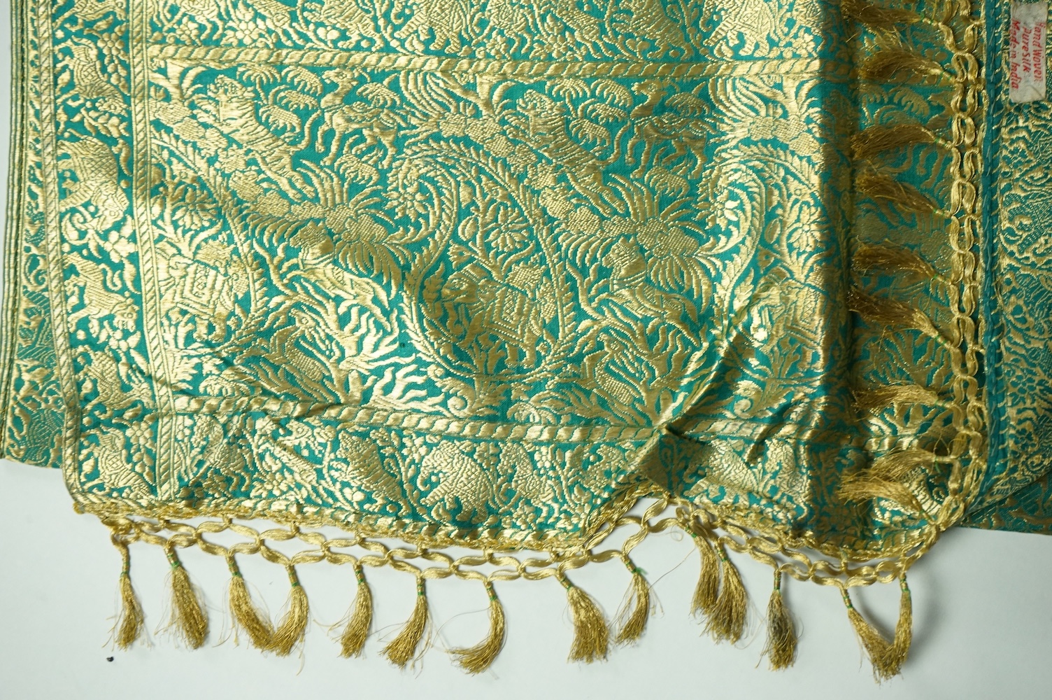 An Indian green and gold silk hand woven brocade stole, a cream pashmina embroidered stole and a similar finely woven and embroidered lilac stole (3). Brocade stole 38cm x 180cm., Condition - light stain to finely woven